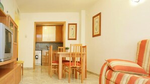 Un espacio habitable compacto con kitchenette, muebles de madera y un sofá a rayas.
