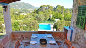 Comedor con una mesa dispuesta para seis personas, con vista a una piscina y exuberante vegetación.