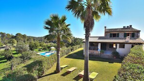 Una villa con piscina, palmeras y césped cuidado.