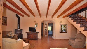 Amplia sala de estar con chimenea, televisor y una escalera que sube a un nivel superior.