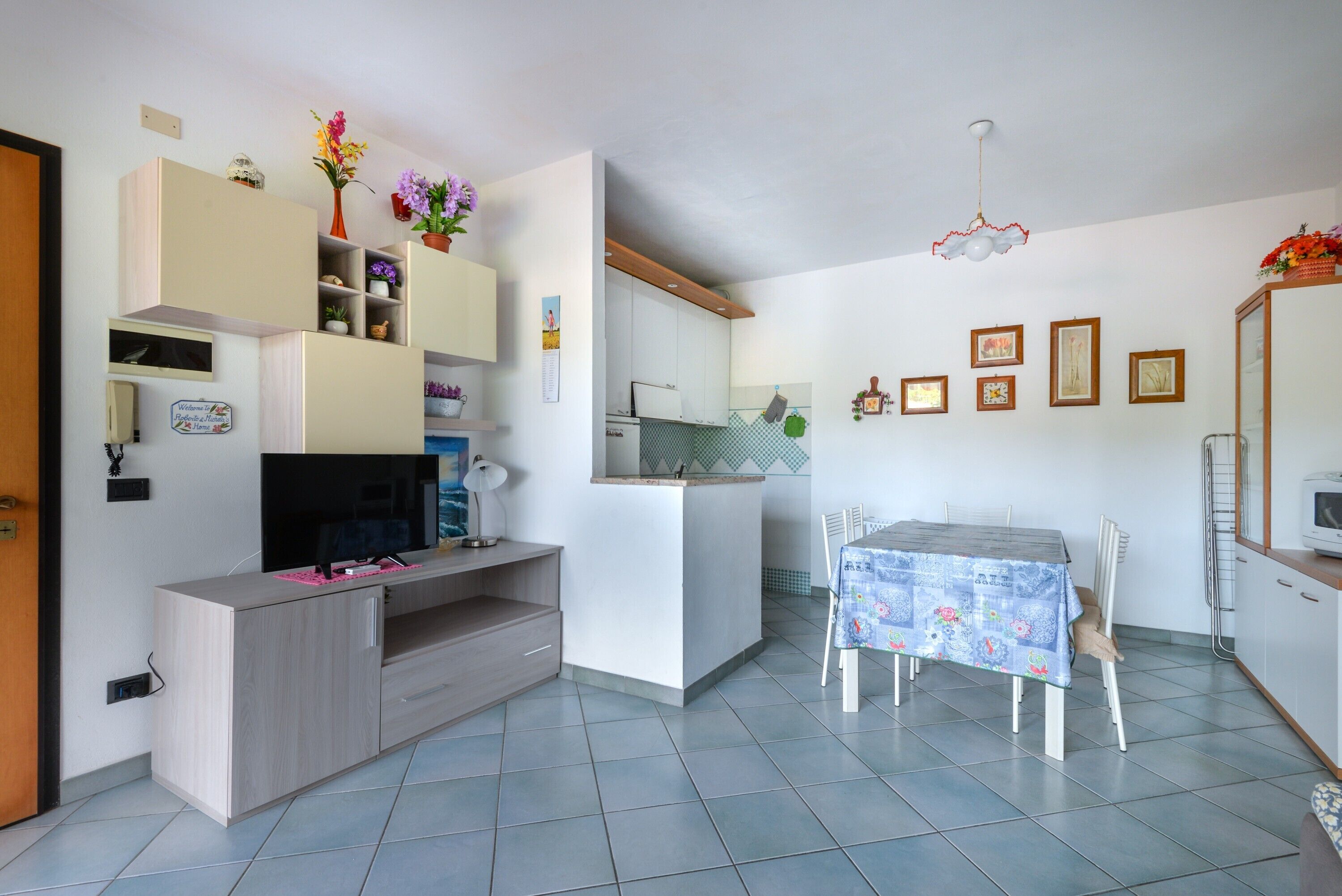 A modern kitchen with a dining area, a TV, and a small island.