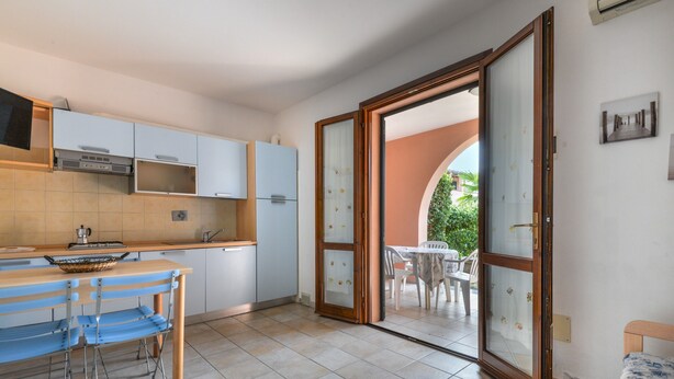 A kitchen with a dining area, a sliding glass door to an outdoor patio, and a bed. - Apartment '3B' with Private Terrace and Air Conditioning (Campo nell'Elba)