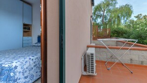 A bedroom with a bed, a wardrobe, and a small shelf. - Apartment '3B' with Private Terrace and Air Conditioning (Campo nell'Elba)