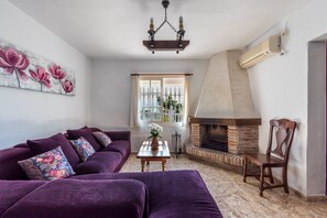 A living room with a sofa set, a fireplace, and a floral painting on the wall.