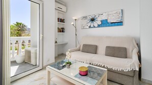 A living room with a sofa, a coffee table, a painting, and a bookshelf. - Bright Apartment Estela Maris with Direct Beach Access (Nerja)