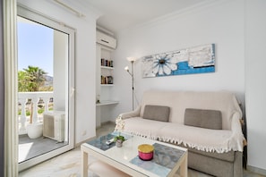 Uma sala de estar com sofá, mesa de centro, quadro e estante de livros.