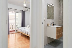 Une chambre avec un lit, une salle de bain avec un lavabo et un miroir, et un balcon avec vue.