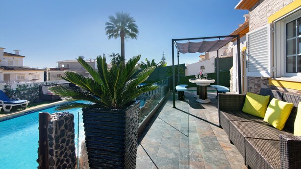 A rooftop pool area with a stone planter, outdoor furniture, and a view of neighboring buildings. - Mediterranean Villa "Calipso" with Wi-Fi, Terrace and Pool (Albufeira)