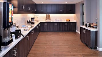 Una cocina moderna con armarios de madera oscura, una encimera blanca y una cafetera.