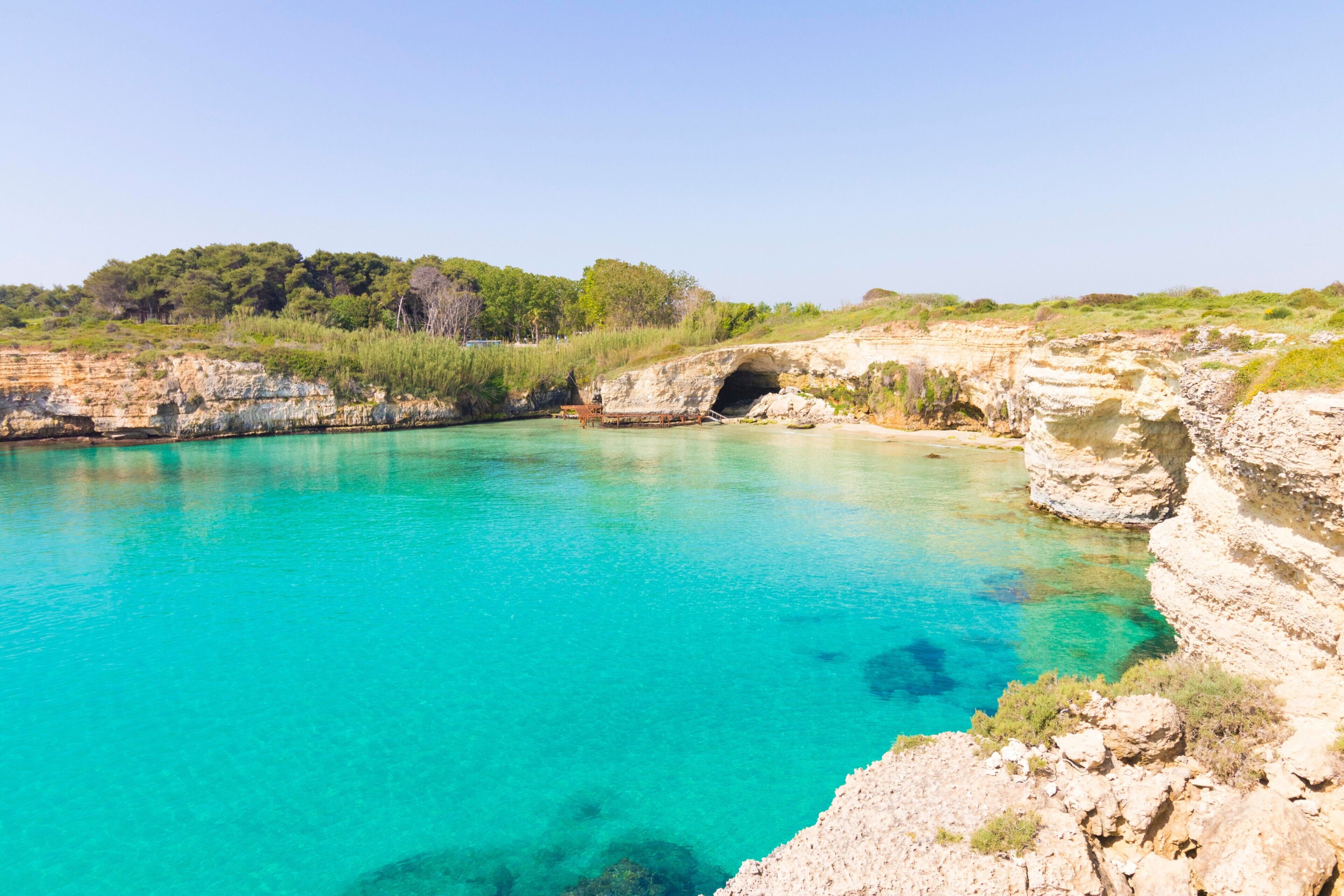 A natural pool surrounded by rocky cliffs and greenery.