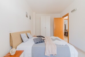 A bedroom with a bed, bedside table, and a wooden door leading to another room.
