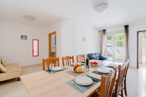 A dining area with a table set for four, chairs, a sofa, and a view of the outdoors.