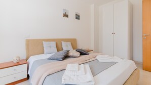 Ein Schlafzimmer mit Bett, Kissen, einem Nachttisch, einem Holzschrank und zwei Wandbildern.