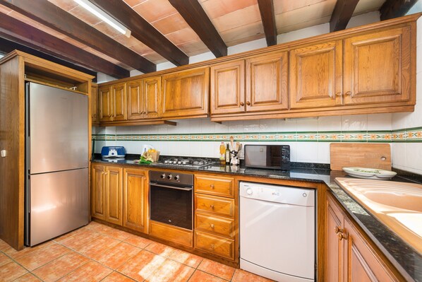 A kitchen with wooden cabinets, a stainless steel refrigerator, a dishwasher, and a stove. - Finca in Idyllic Location with Terrace, Pool and Wi-Fi (Pollensa)