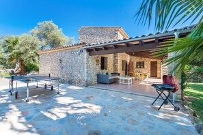 A stone building with a patio area, outdoor seating, and a grill.