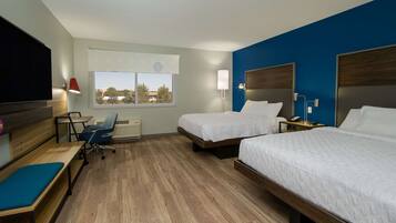 A hotel room with two beds, a desk, a chair, a TV, and a window with a view.