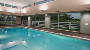 Una piscina con agua cristalina, rodeada de grandes ventanales y una valla blanca.