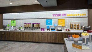 Una estación de desayuno con diversas opciones de comida y un letrero que dice 'Top It Breakfast'.
