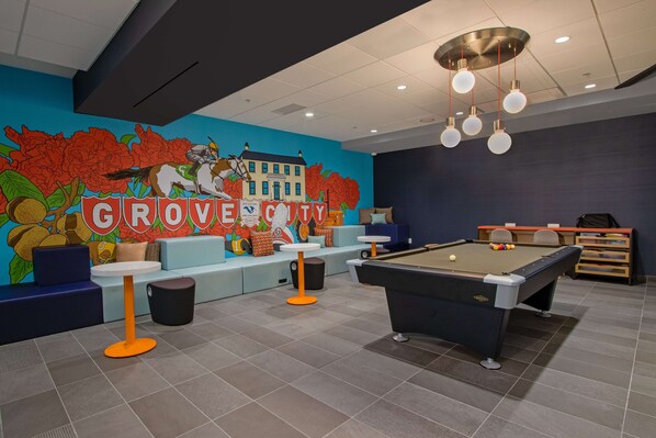 A billiards room with a pool table, seating area, and a mural of Grover Cleveland.