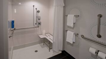 A modern bathroom with a shower, grab bars, a towel rack, and a toilet paper holder.