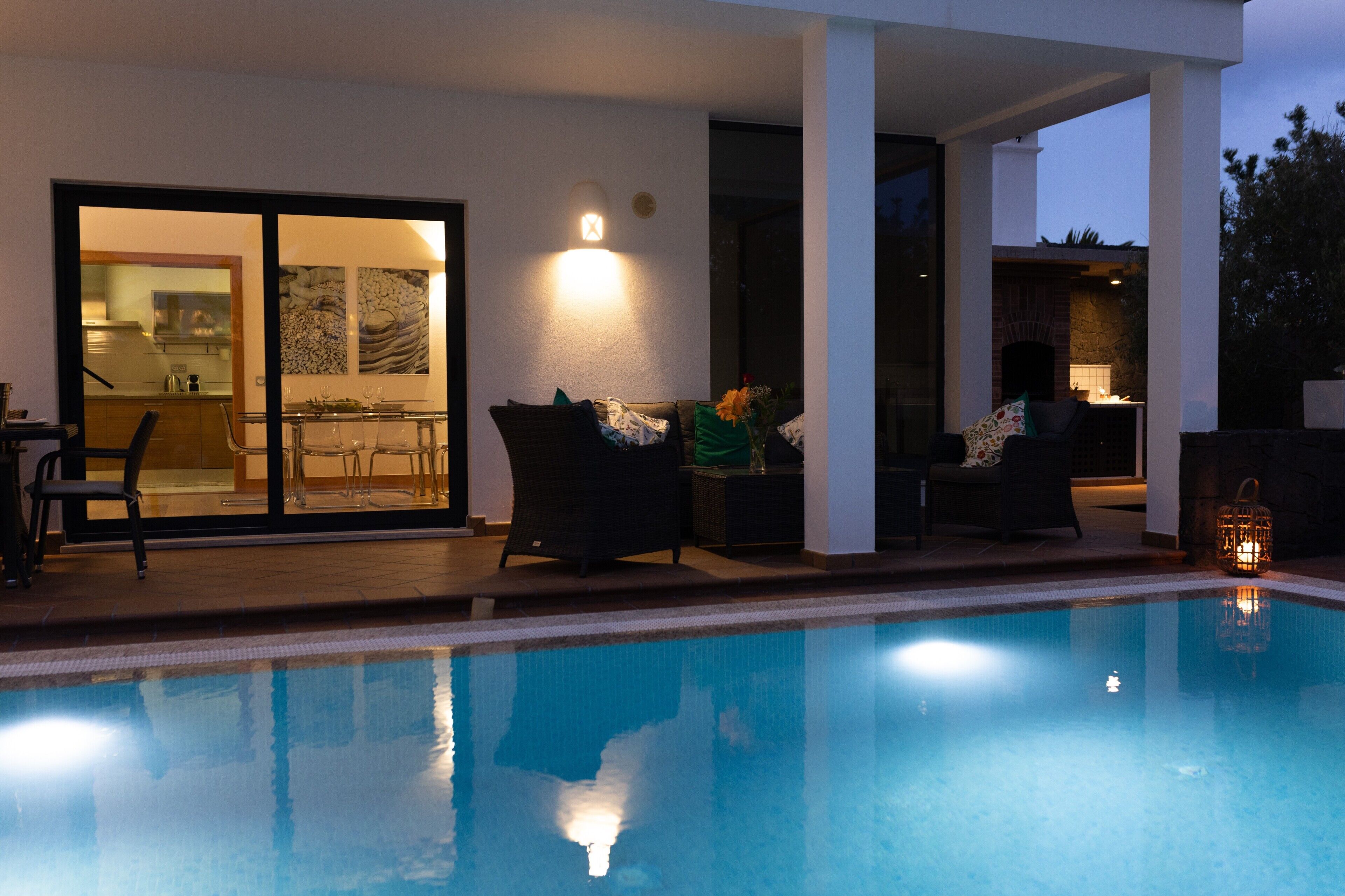 A swimming pool with a glass enclosure, outdoor seating, and a fireplace.