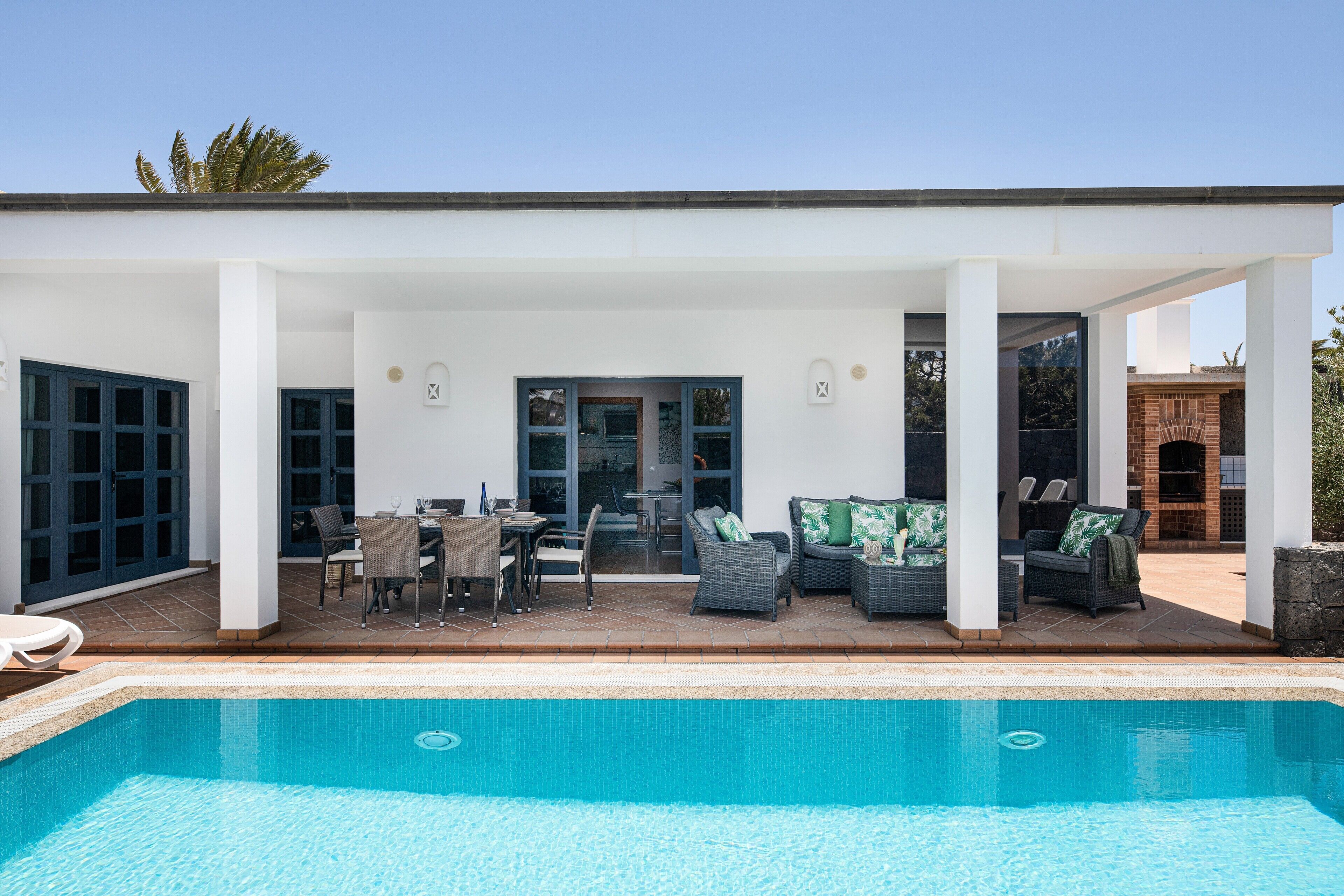A covered outdoor area with a pool, seating, and a view of the interior.