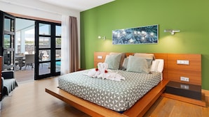 Une chambre d’hôtel moderne avec un grand lit, un mur vert, un tableau et une vue sur l’espace extérieur.