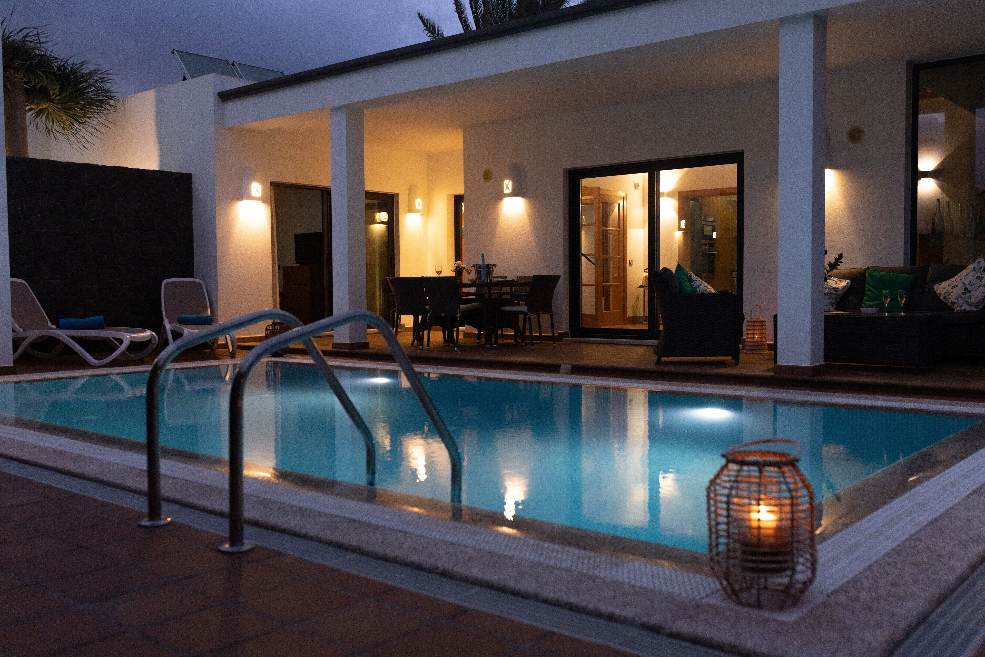 Une piscine dotée d’un espace salon aménagé en contrebas, d’une table à manger et d’un canapé.