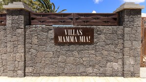 Un mur de pierre sur lequel est apposée une enseigne indiquant : « VILLAS MAMMA MIA ! »