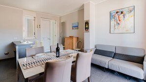A modern dining area with a table set for two, a sofa, and a cabinet.