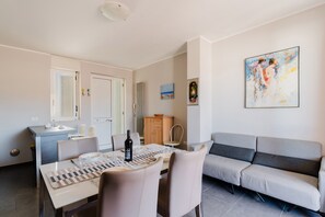 Un espace repas moderne avec une table dressée pour deux personnes, un canapé et un meuble.