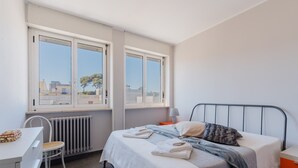 A bedroom with a bed, a chair, a desk, and a window.