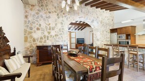 Ein Essbereich mit Steinwand, Holzmöbeln und einem Fernseher im Hintergrund.