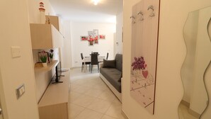 Un salon moderne comprenant un canapé, une table à manger avec des chaises et un coin cuisine avec des placards et un plan de travail.