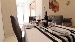 Un coin repas avec une table dressée pour deux personnes, une bouteille de vin et une horloge au mur.