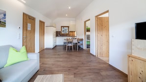 Un espace de vie moderne comprenant un canapé, un plancher en bois, un coin repas et une cuisine en arrière-plan.