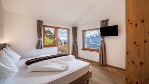 Une chambre à coucher avec un lit, une télévision et de grandes fenêtres équipées de rideaux.