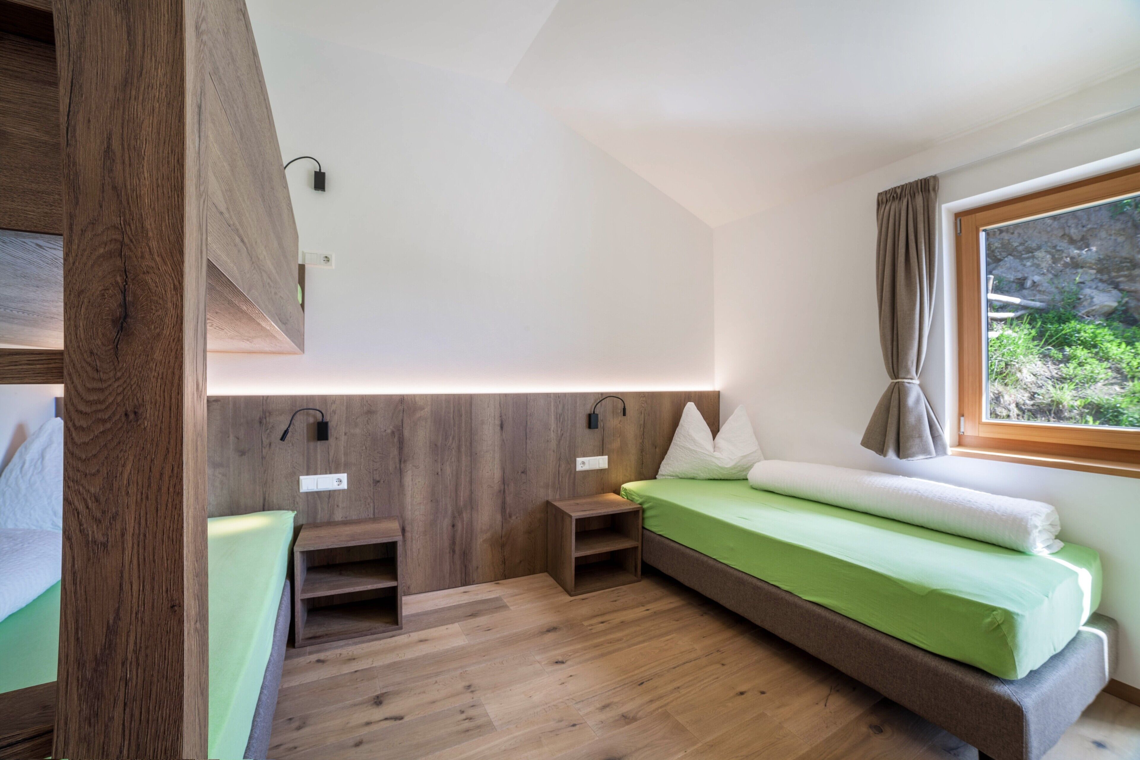 Una habitación pequeña con cama, escritorio y ventana con cortinas.