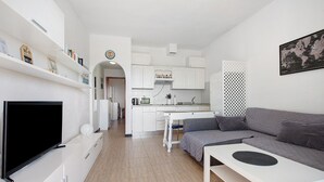 Una sala de estar moderna con un televisor de pantalla plana, un sofá gris y una mesa de centro blanca.