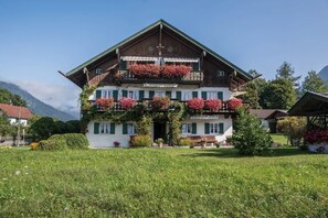 A traditional wooden house with balconies, a front porch, and a well-maintained garden.