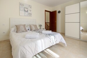 Une chambre à coucher comprenant un lit, une table de chevet, une lampe, une horloge et une armoire.