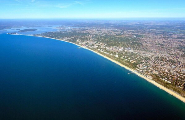 An aerial view of a coastal city with a long beach, dense urban area, and clear blue waters. - Brooklands Lodge (Bournemouth)