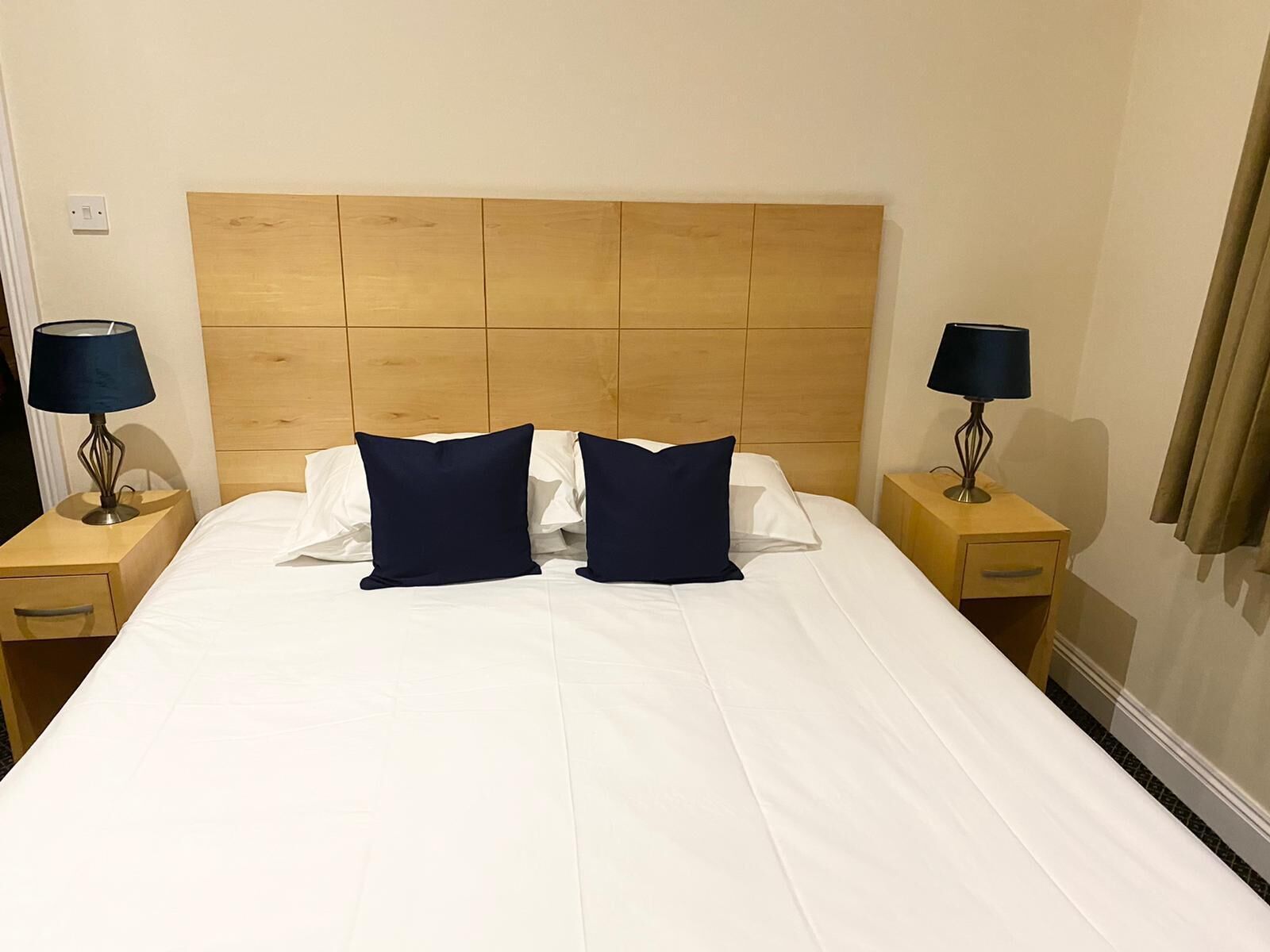 Ein Hotelzimmer mit einem großen Bett, zwei Nachttischen und zwei Lampen.