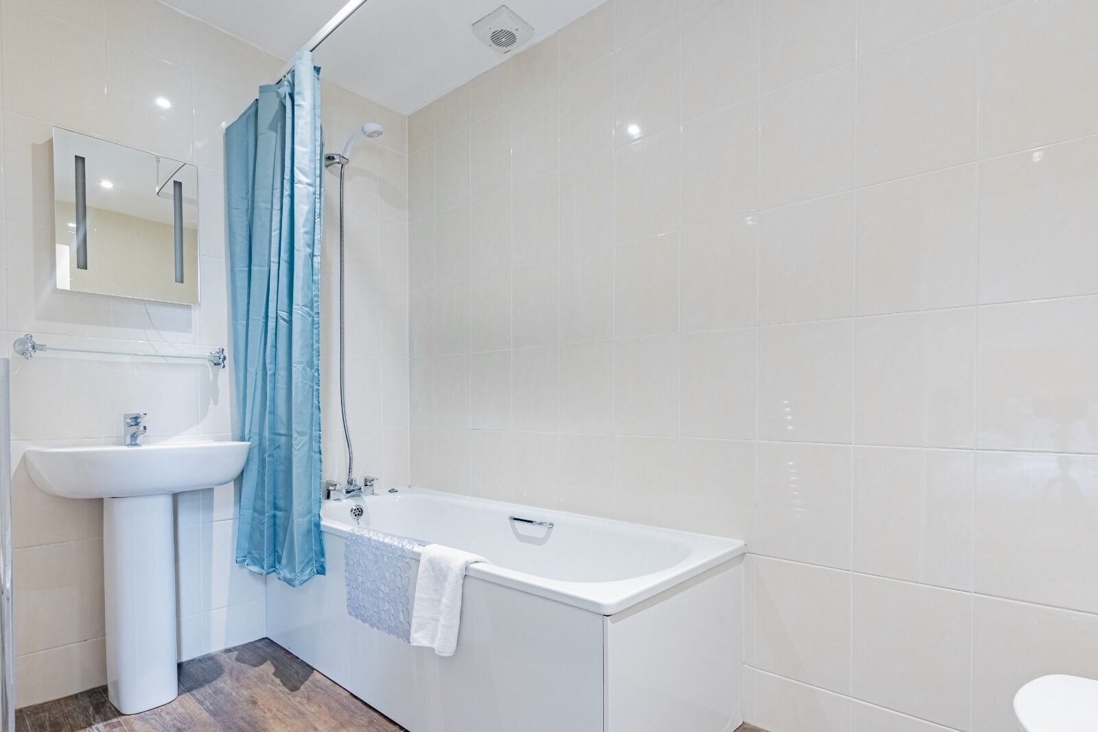 Un baño moderno con lavamanos blanco, bañera y cortina de ducha.