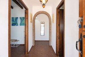 A hallway with a herringbone floor, a wooden door frame, and a hanging light fixture.