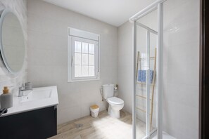 Un baño con lavamanos blanco, inodoro y cabina de ducha de vidrio.