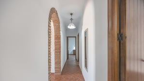A hallway with a brick column, wooden door, and a hanging light fixture. - Family Home "La Lobita 1" Short Drive from Beach with Pool, Terrace and Wi-Fi (Conil de la Frontera)