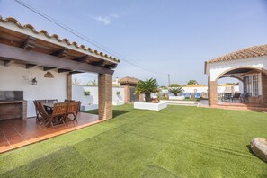 Un patio con una parrilla, mobiliario exterior y un césped bien cuidado.