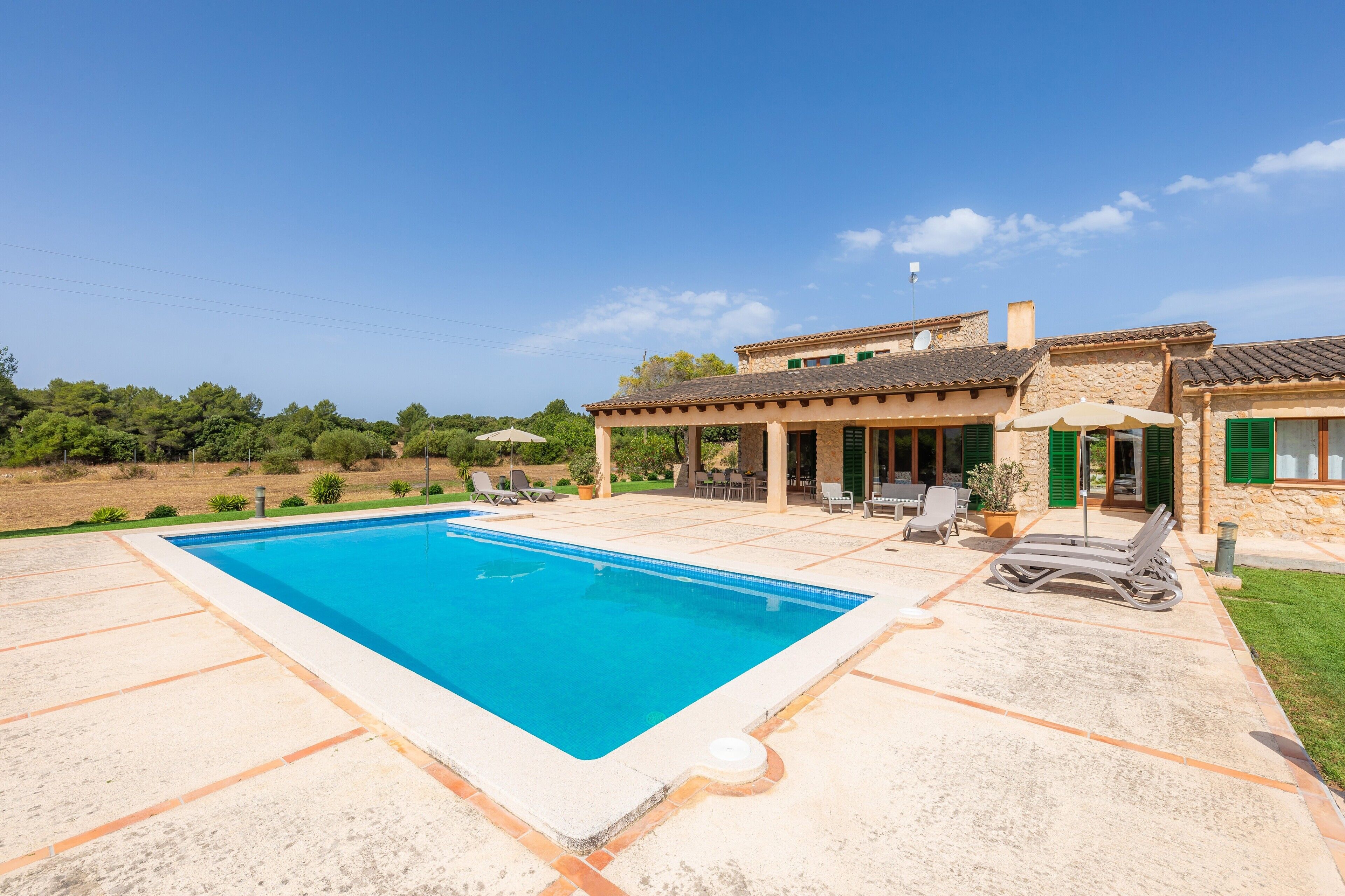 A swimming pool with lounge chairs and a covered patio area.