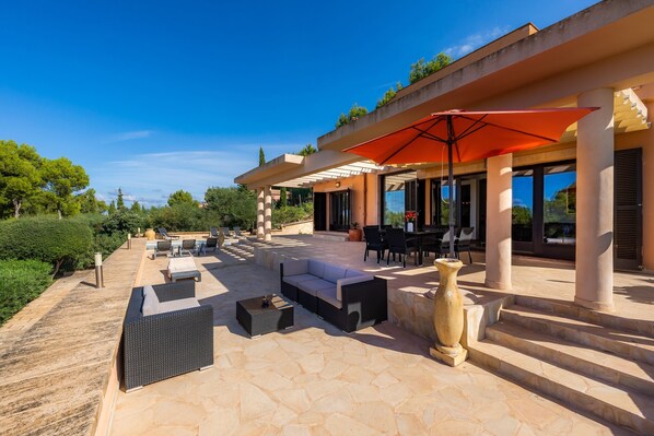 An outdoor patio with seating, a table, and a large umbrella.